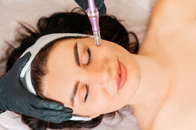 Woman receiving a facial treatment with a beauty device.